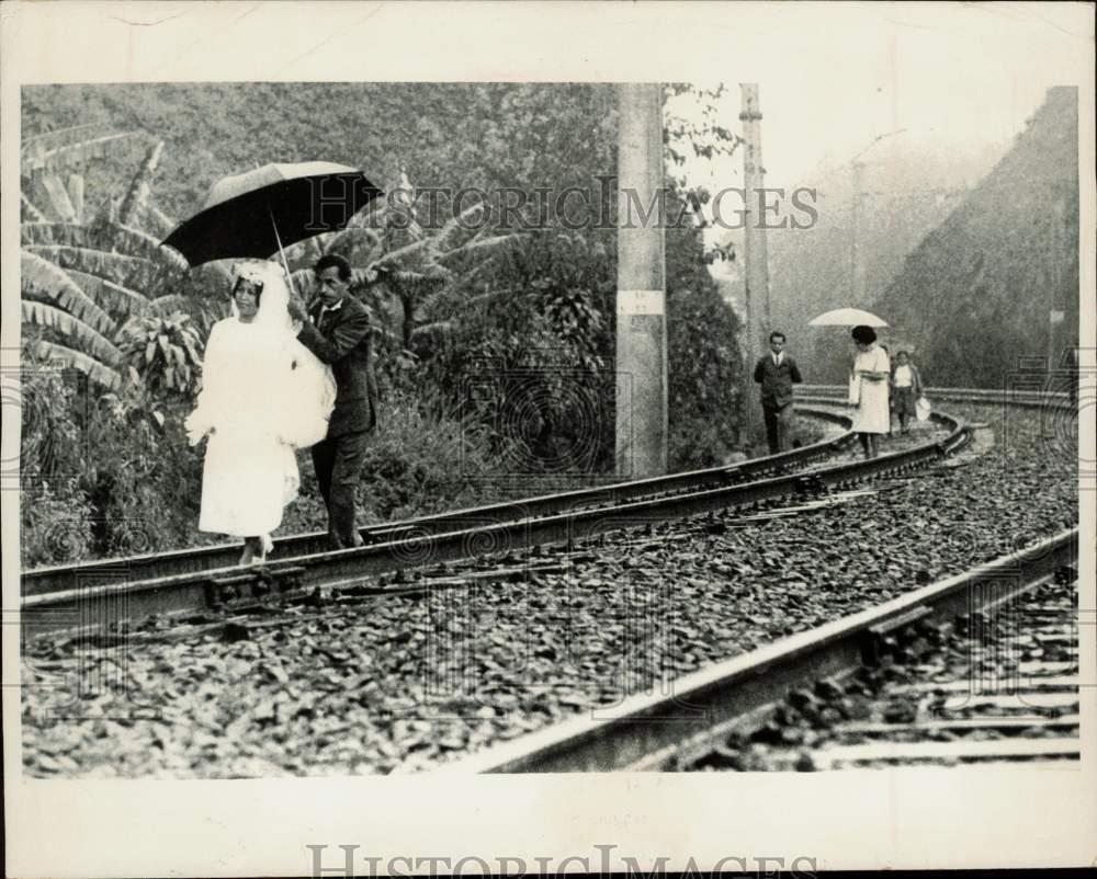 1971 Press Photo Man holds train of his bride's dress on railroad track, Brazil