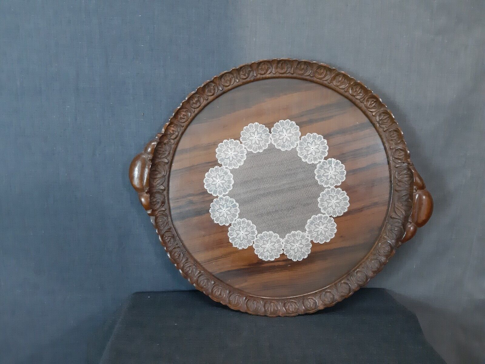 Old unique tray with fine wooden carving around the rim with lace under glass
