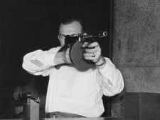 Man wearing a white shirt taking aim a Thompson submachine gun, al Old Photo picture